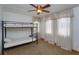 Neutral bedroom with a bunk bed, ceiling fan, and sun-drenched windows with curtains at 36408 E Eldorado Lake Dr, Eustis, FL 32736