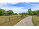 Long driveway leading to a home with a large lawn, mature trees, and a rustic fence at 36408 E Eldorado Lake Dr, Eustis, FL 32736