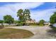 Home featuring a large concrete parking area and mature trees at 36408 E Eldorado Lake Dr, Eustis, FL 32736