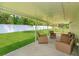 Spacious covered patio area with multiple seating options, overlooking the well-maintained lawn and white picket fence at 36408 E Eldorado Lake Dr, Eustis, FL 32736