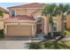 Charming two-story home featuring a red tile roof, arched doorway, and well-maintained landscaping with mature palm trees at 411 Cabello Dr, Davenport, FL 33837