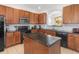 Well-equipped kitchen featuring wood cabinetry, black appliances, granite countertops and a central island at 411 Cabello Dr, Davenport, FL 33837