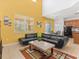 Living room with a comfortable black sofa, modern decor, and open access to the eat-in kitchen area at 411 Cabello Dr, Davenport, FL 33837