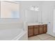 A bright main bathroom with a soaking tub, vanity with sink, and a large framed mirror at 411 Cabello Dr, Davenport, FL 33837