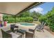 Relaxing covered patio seating area near the pool, surrounded by lush landscaping, and providing a private outdoor space at 5056 Gandross Ln, Mount Dora, FL 32757