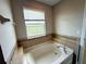 Inviting bathroom with a soaking tub, tile surround and a bright window at 5213 Northlawn Way, Orlando, FL 32811