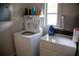 Bright laundry room featuring a washer, dryer, storage shelf, and a window at 704 Beverly Ave, Altamonte Springs, FL 32701
