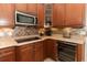 Close up of kitchen featuring stainless steel microwave, wine refrigerator, and tile backsplash at 753 Grey Heron Pl, Chuluota, FL 32766