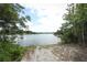 Picturesque lake view with a sandy path leading to the water, framed by lush greenery and a blue sky at 753 Grey Heron Pl, Chuluota, FL 32766