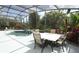 Inviting screened-in pool area with a dining table, chairs, and a view of lush greenery at 753 Grey Heron Pl, Chuluota, FL 32766