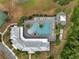 Overhead shot of a community pool surrounded by palm trees, lounge chairs and a gazebo, next to the tennis courts and parking area at 7651 Five Oaks Dr, Harmony, FL 34773