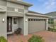 The home's brick driveway, two-car garage, and landscaped yard complement the modern architecture at 7651 Five Oaks Dr, Harmony, FL 34773