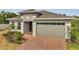 A well-maintained single-Gathering home with a brick driveway, two-car garage, and neatly landscaped front yard at 7651 Five Oaks Dr, Harmony, FL 34773