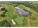 Breathtaking aerial view of a lush green golf course, sand traps and serene lake on a sunny day at 7651 Five Oaks Dr, Harmony, FL 34773