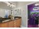 Bathroom featuring a dual sink vanity with granite countertops, and a view into a purple office at 841 Oaks Shores Rd, Leesburg, FL 34748