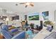 Open living room with a large TV, modern furniture, and a view into the kitchen at 841 Oaks Shores Rd, Leesburg, FL 34748