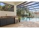 Outdoor pool area with a built-in grill, mini-fridge, lush landscaping, and screened-in enclosure at 841 Oaks Shores Rd, Leesburg, FL 34748