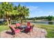 Inviting backyard patio with outdoor seating and a serene pond view surrounded by lush palm trees at 9020 Breezy Meadow Way, Orlando, FL 32829