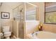 Bright bathroom featuring a glass-enclosed shower, separate tub, and a large window offering natural light at 9020 Breezy Meadow Way, Orlando, FL 32829
