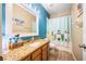 Bathroom featuring a granite countertop vanity, surfboard decor, and a shower-tub combo with a cheerful curtain at 9020 Breezy Meadow Way, Orlando, FL 32829