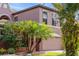 View of a two-story home with attached two-car garage and tropical landscaping at 9020 Breezy Meadow Way, Orlando, FL 32829