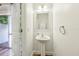 Clean half bathroom featuring a pedestal sink, framed mirror, and modern fixtures at 10404 Park Commons Dr, Orlando, FL 32832