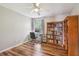 Cozy office with wood floors, ceiling fan, a desk, rolling chair and a bookshelf at 10404 Park Commons Dr, Orlando, FL 32832
