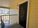 Apartment entryway with a black front door, showing the exterior yellow siding and a partial view of the complex at 1081 S Hiawassee Rd # 726, Orlando, FL 32835