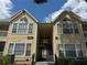 Two-story condo with bright yellow siding, white trim and decorative windows under a partly cloudy blue sky at 1081 S Hiawassee Rd # 726, Orlando, FL 32835