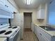 Galley kitchen with white cabinets, appliances and a laundry closet with washer and dryer hookups at 1081 S Hiawassee Rd # 726, Orlando, FL 32835