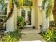 Close-up of double front doors with stained glass, flanked by columns and tropical plants with a stone walkway at 1121 Arbor Glen Cir, Winter Springs, FL 32708