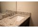Bathroom vanity with a speckled granite countertop, modern faucet, and a white sink at 1286 Shoreside St, Clermont, FL 34714