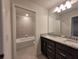 Bright bathroom featuring a granite countertop with dual sinks and a tub with tiled wall at 1286 Shoreside St, Clermont, FL 34714
