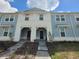 Inviting townhome with a light blue exterior, covered entries, and fresh landscaping at 1286 Shoreside St, Clermont, FL 34714