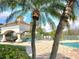 Community pool view featuring palm trees, shaded tables and lounge chairs at 14001 Fairway Island Dr # 513, Orlando, FL 32837