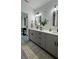 Modern bathroom featuring double vanity, updated fixtures, decorative plant and stylish gray vinyl plank flooring at 1412 Pine St, Orlando, FL 32824