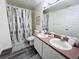 Bathroom with double sink vanity, shower with patterned curtain, and wood-look floors at 143 Windsor Pl, Davenport, FL 33896
