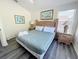 Comfortable bedroom features a queen bed with 2 nightstands, windows, and wood-look floors at 143 Windsor Pl, Davenport, FL 33896