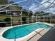 Sparkling pool and spa under a screened enclosure, complemented by mature trees and manicured lawn at 143 Windsor Pl, Davenport, FL 33896