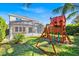Large backyard featuring lush greenery and a wooden playset, complemented by the home's screened lanai at 14518 Black Quill Dr, Winter Garden, FL 34787