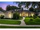 Beautiful home with a lush green lawn, manicured landscaping, and elegant architectural details at dusk at 1525 Eagle Nest Cir, Winter Springs, FL 32708