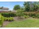 Landscaped backyard featuring green grass, mulch, bushes, and a wooden fence at 1618 Pepperidge Dr, Orlando, FL 32806