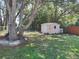 View of the backyard featuring a pink shed, mature trees, and a fenced-in yard providing a private outdoor space at 1620 Carolyn Ct, St Cloud, FL 34769