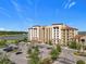 Aerial view of condo building, parking lot, landscaping, and lake in the distance on a beautiful day at 16300 County Road 455 # 405, Montverde, FL 34756