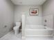 Bright bathroom featuring a white tiled tub and toilet, complemented by neutral gray walls and marble flooring at 16300 County Road 455 # 405, Montverde, FL 34756
