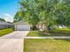 Charming single-story home features a well-maintained lawn, mature tree, and a two-car garage at 20446 Macon Pkwy, Orlando, FL 32833