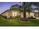 Landscaped front yard features a decorative palm tree and manicured lawn, with a three car garage in the background at 2086 Biller Cir, The Villages, FL 32163