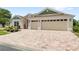 Beautiful home featuring a three car garage and brick paver driveway, complimented by lush landscaping at 2086 Biller Cir, The Villages, FL 32163