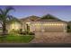 Beautiful house with a three car garage and manicured yard with a mature palm tree and brick paver driveway at 2086 Biller Cir, The Villages, FL 32163