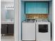 Convenient laundry room featuring modern washer and dryer, with stylish blue cabinets and mosaic tile backsplash at 408 S Winsome Ct, Lake Mary, FL 32746